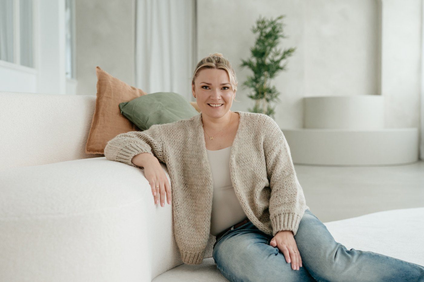 Mandy Jäger sitzt entspannt auf einem hellen Sofa im Praxisraum