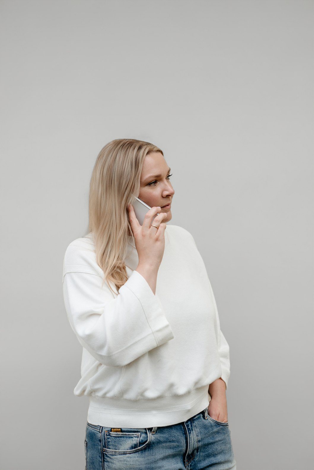 Mandy Jäger steht vor einer hellen Wand und telefoniert