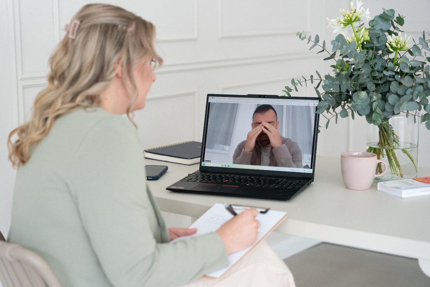Mandy Jäger sitzt am Schreibtisch vor einem Laptop und spricht in einem Videogespräch mit einer Person