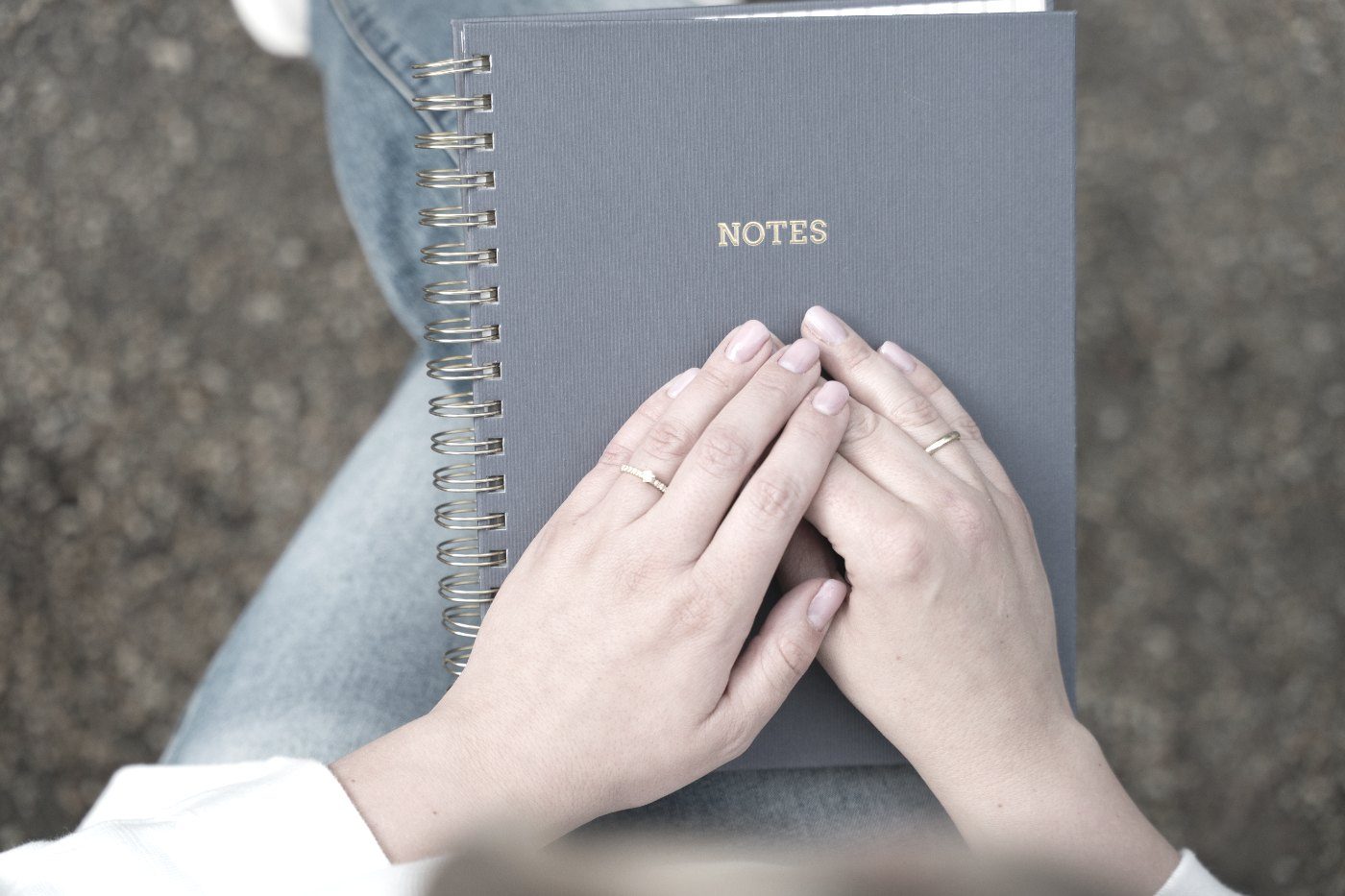 Zwei Hände liegen ruhig auf einem geschlossenen Notizbuch
